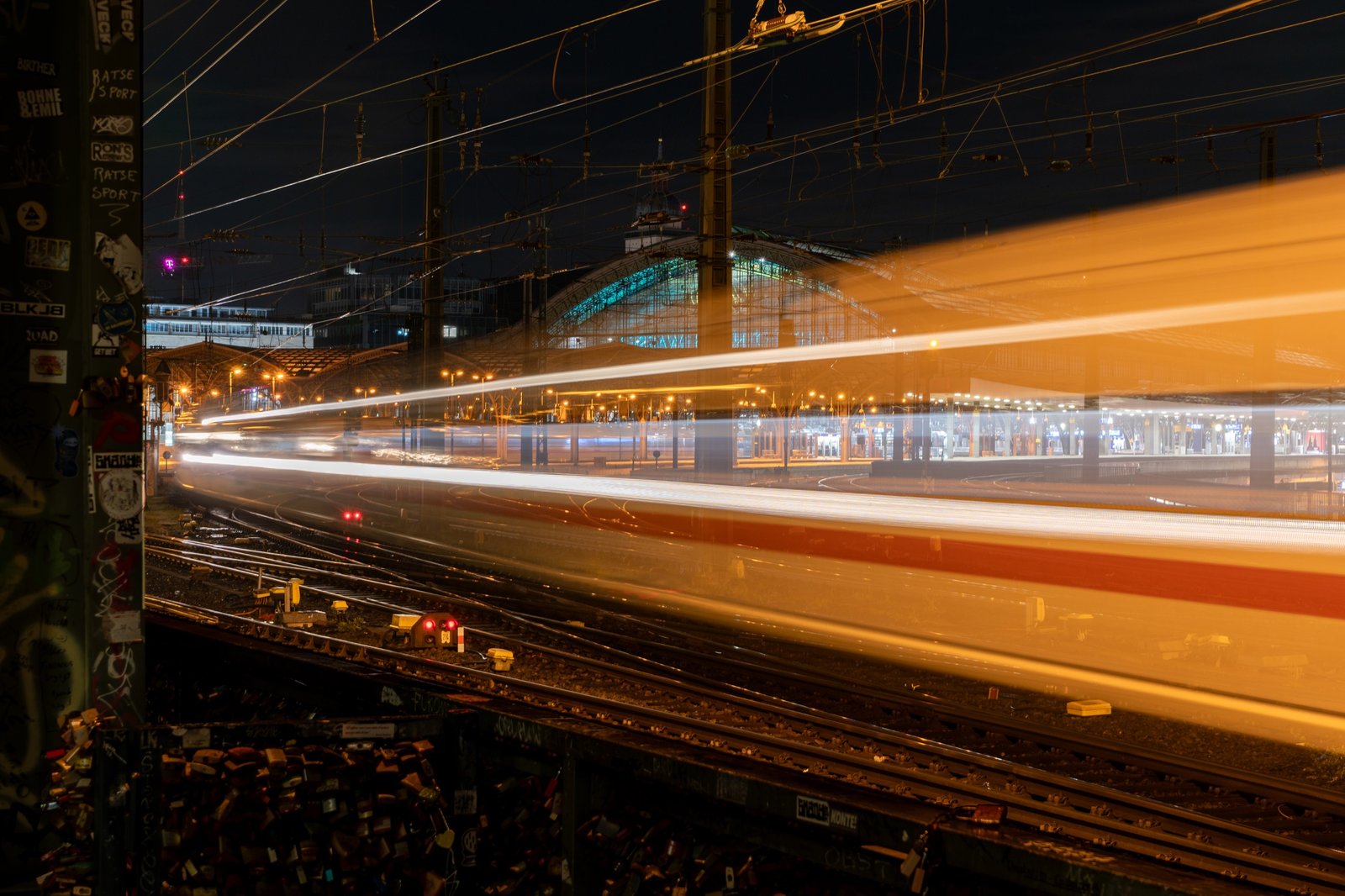 Long-exposure light trails crossing a rail station at night