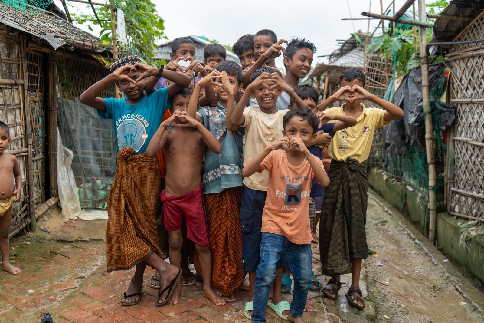 Children in a refugee settlement forming heart shapes with their hands