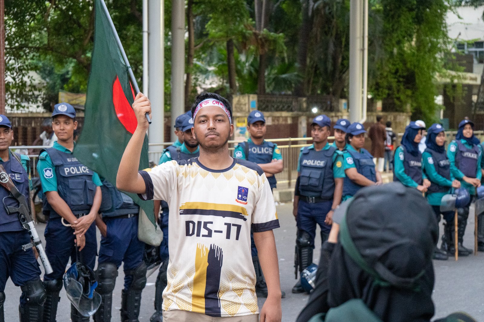 Dhaka University student waves a Bangladesh flag in front of a police line