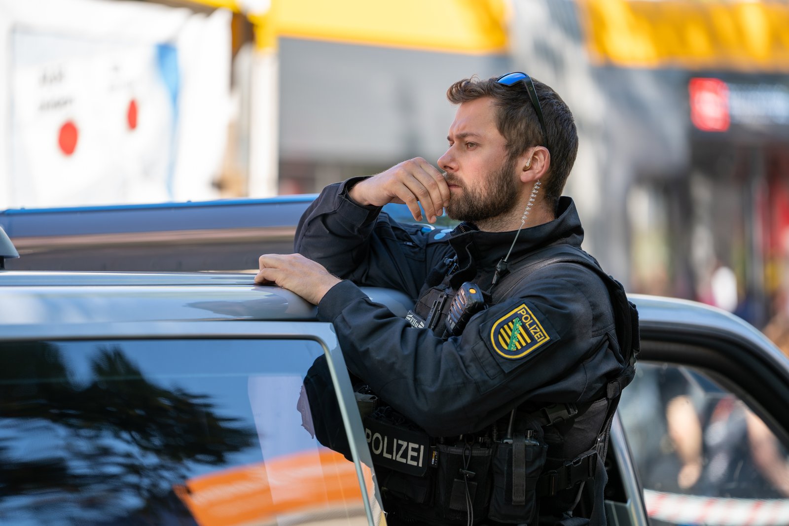 Police officer leaning against a patrol car during the Leipzig Labor Day march