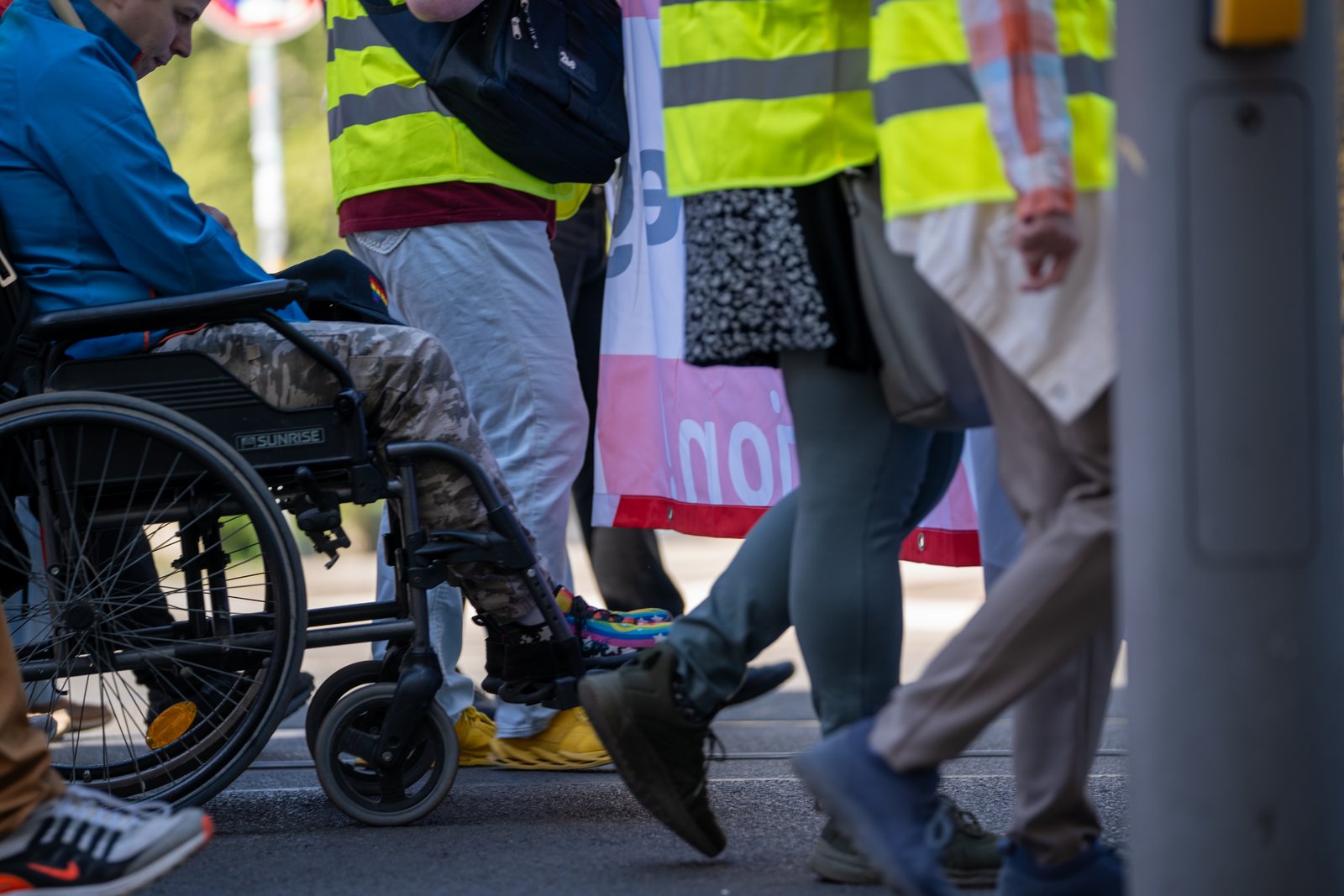 Wheelchair user moving with the Leipzig Labor Day parade behind union banners