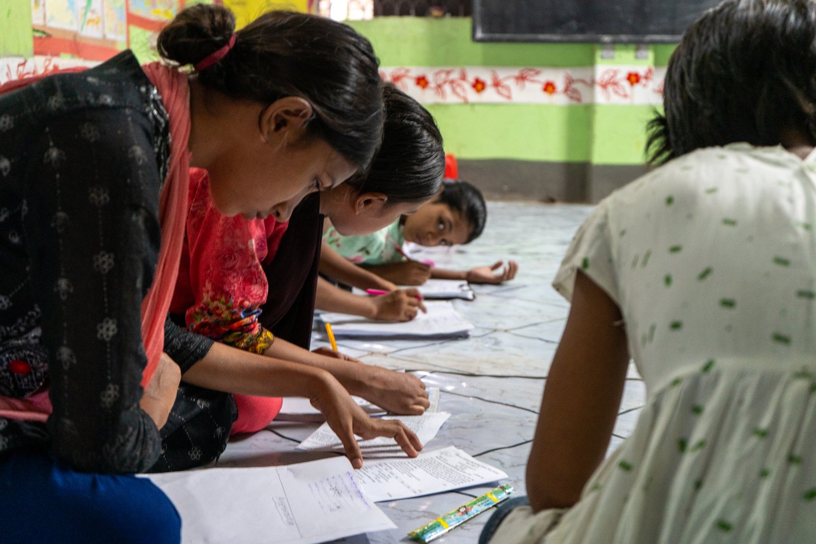 Children leaning over schoolwork during a classroom lesson in Mirpur