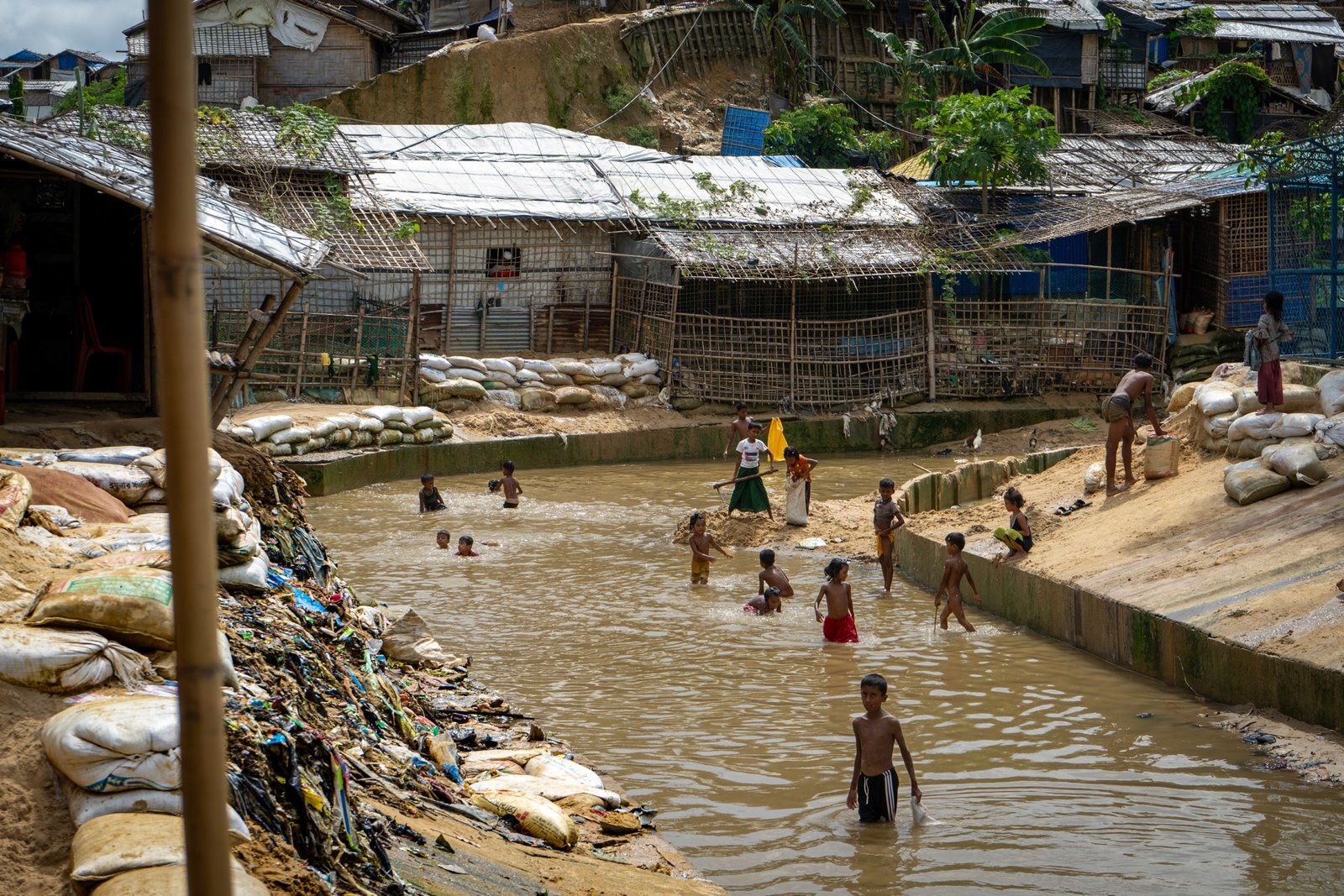 Wide view of settlement roofs and a water channel where children play