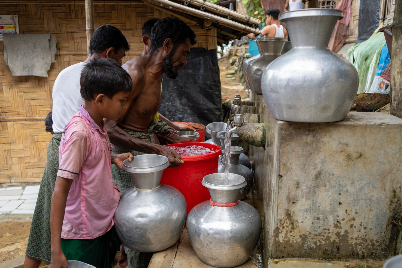 Residents filling containers at a camp water point with taps and buckets