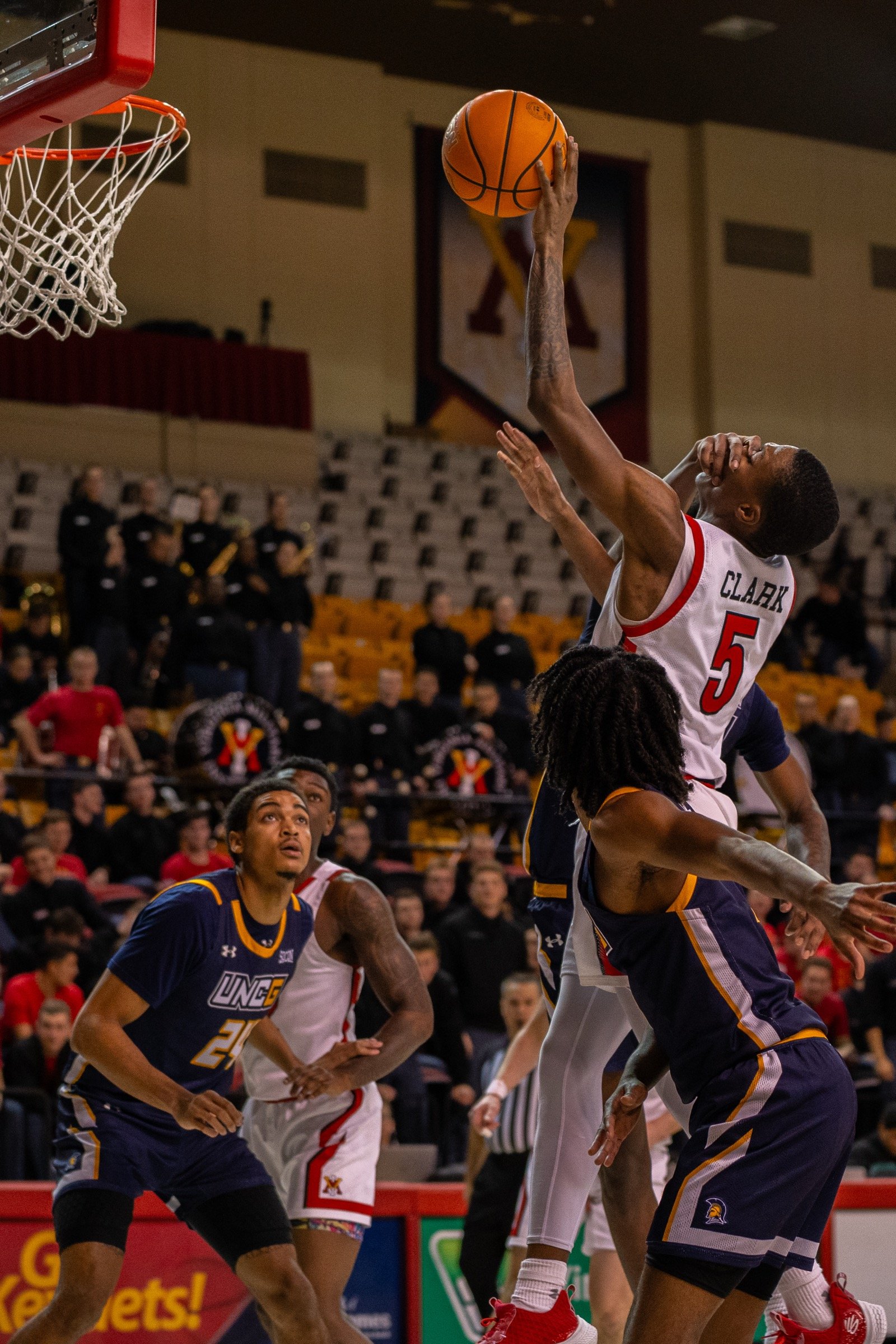 Basketball player extending for a layup against defenders at the rim