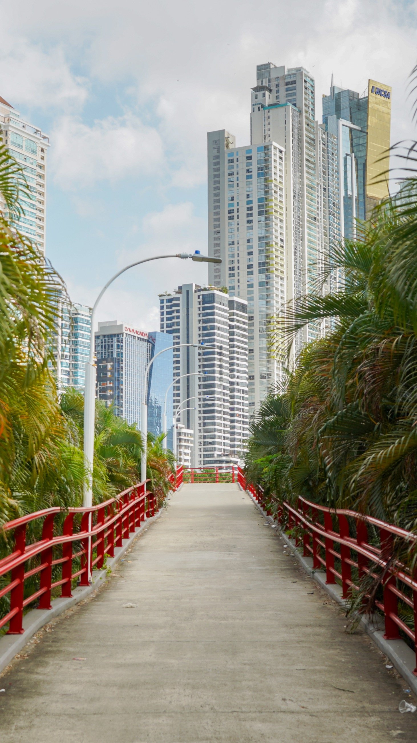 Elevated walkway leading toward modern towers and palm trees