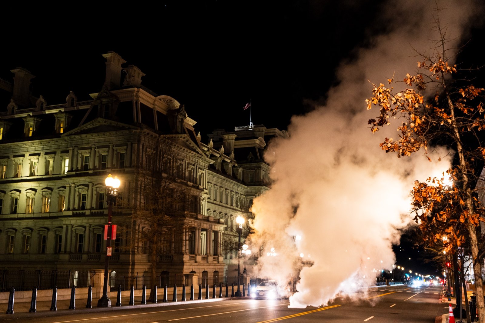 Steam rising beside ornate buildings on a city street at night