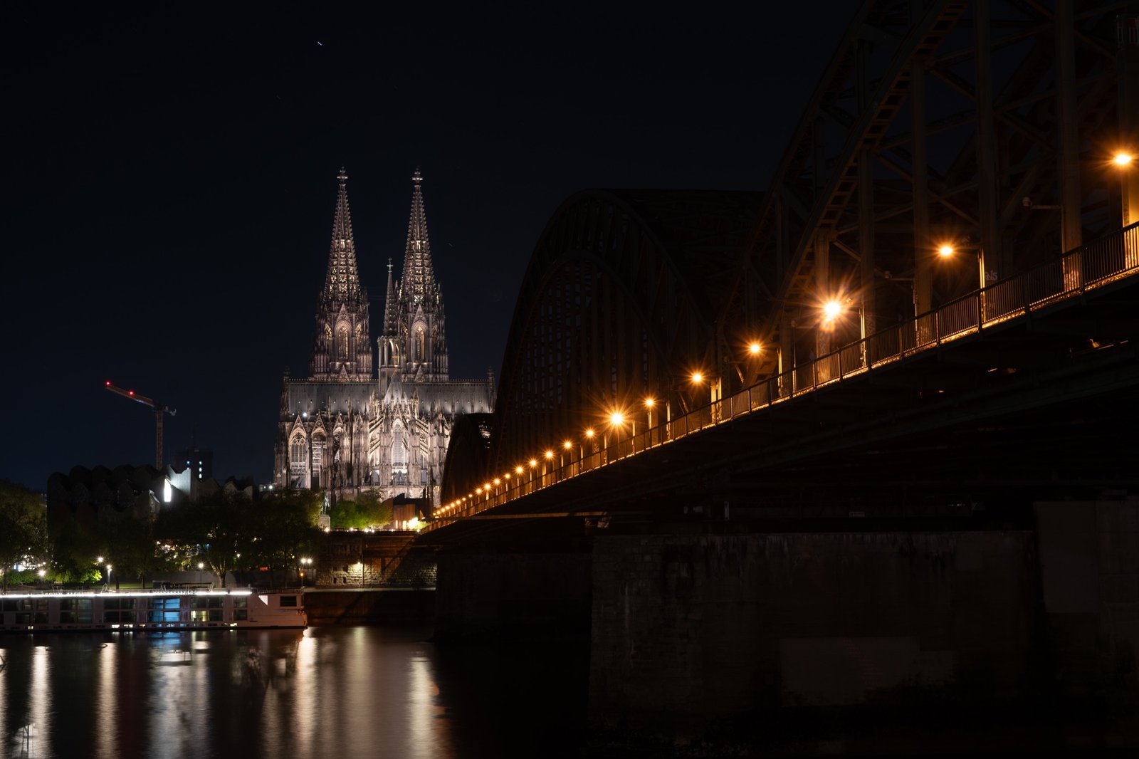 Cathedral towers and bridge lights reflected across a river at night